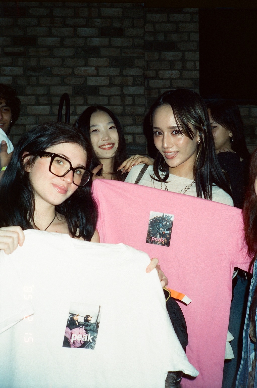 Noa and friends holding Peak merch shirts at an event