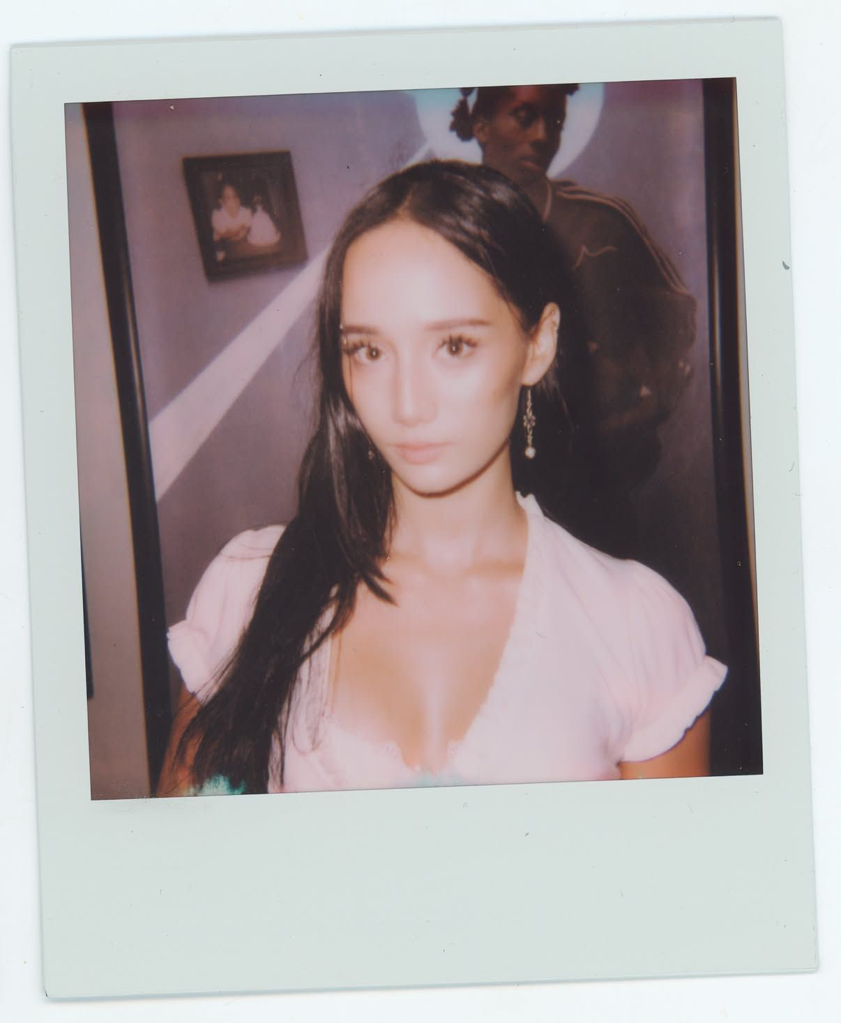 Polaroid portrait of Noa in a pale pink top with drop earrings