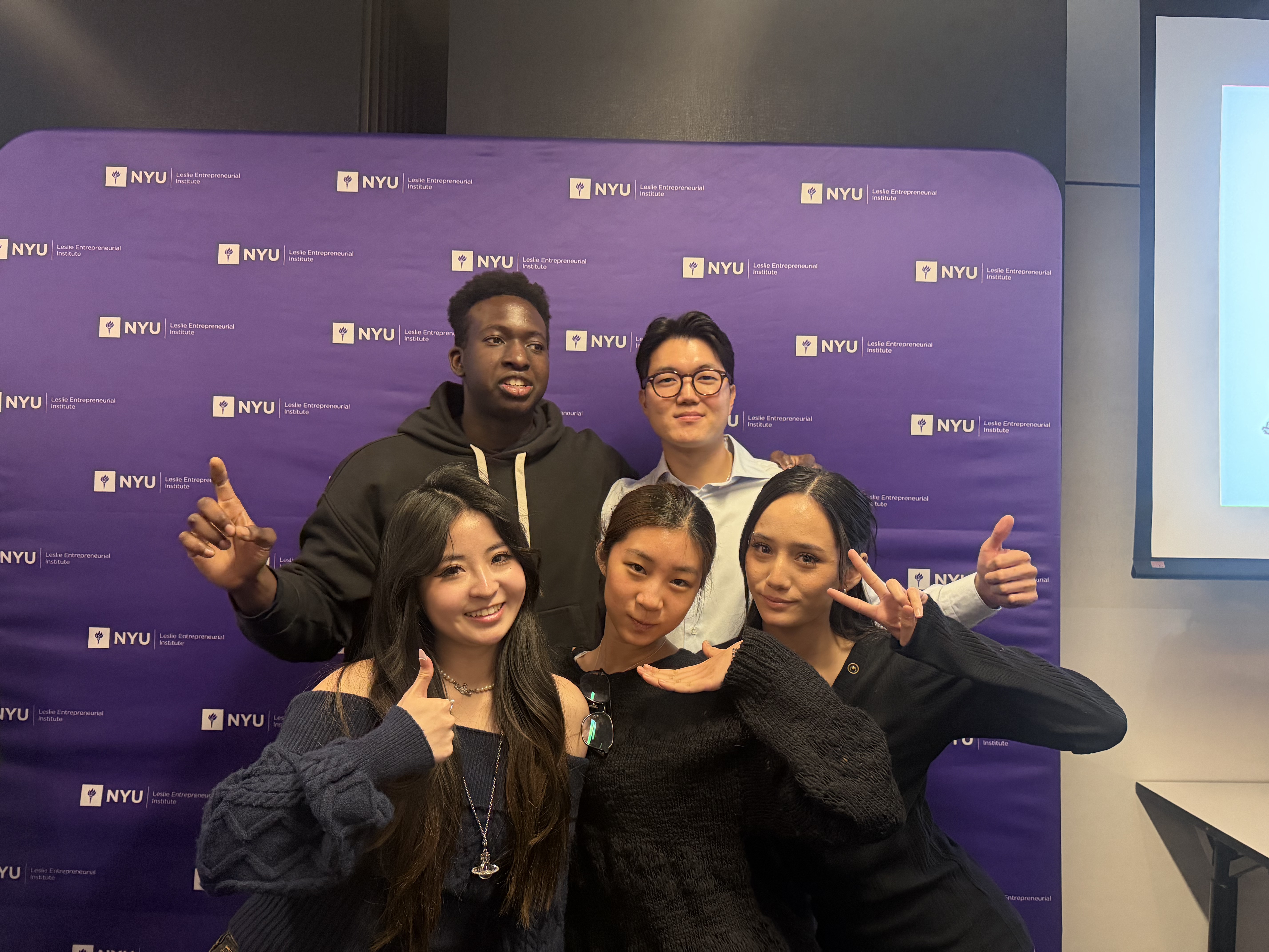 Group photo of Noa and her Honey Bee teammates giving thumbs up in front of an NYU Leslie eLab backdrop